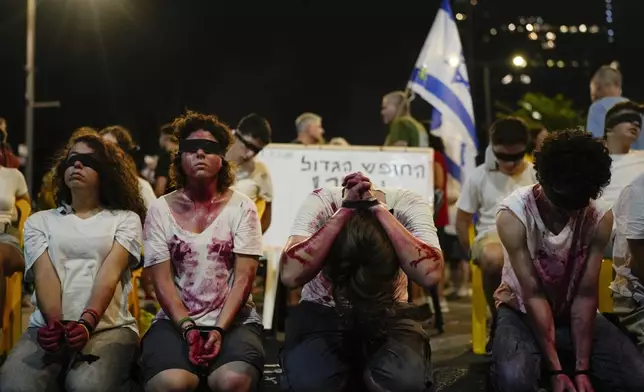 Blindfolded and bounded wrists activists take part in a protest against Israeli Prime Minister Benjamin Netanyahu's government and call for the release of hostages held in the Gaza Strip by the Hamas militant group in Tel Aviv, Israel, Saturday, Aug. 31, 2024. (AP Photo/Ohad Zwigenberg)