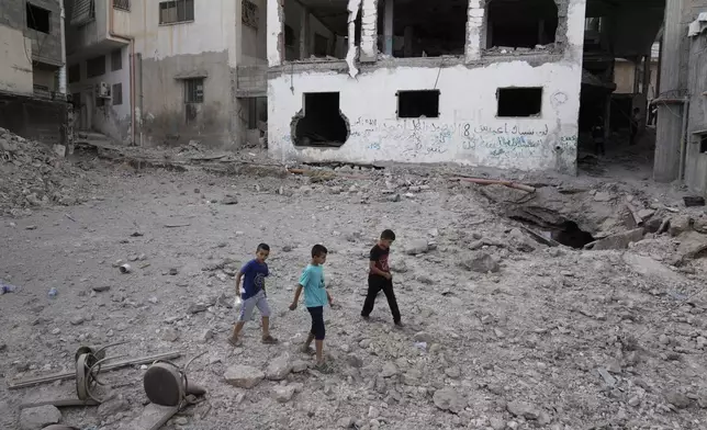 Palestinians walk past a damaged building following an Israeli military operation in the West Bank city of Jenin on Friday, Sept. 6, 2024. (AP Photo/Majdi Mohammed)