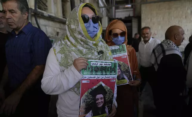 Two fellow activists of Aysenur Ezgi Eygi, 26, who was fatally shot by Israeli soldiers while participating in an anti-settlement protest in the West Bank, carry posters with her name and photo during Eygi's funeral procession in the West Bank city of Nablus, Monday, Sept. 9, 2024. (AP Photo/Nasser Nasser)