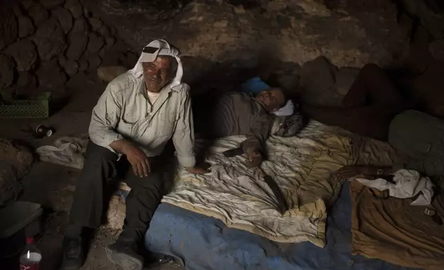 Palestinians Ribhi Ahmad Battat, left, and Issa Ahmad Battat, residents of the West Bank village of Khirbet Zanuta, take shelter from the midday sun in a cave Tuesday, Aug. 27, 2024. Ten months after settlers threatened to kill them if they didn't leave their village, some Palestinian residents are finally home, under a rare court order. (AP Photo/Maya Alleruzzo)