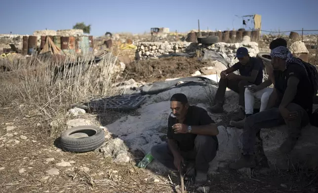 Palestinians rest in the shade in the West Bank village of Khirbet Zanuta, Thursday, Aug. 29, 2024. Ten months after settlers threatened to kill them if they didn't leave their village, some Palestinian residents are finally home, under a rare court order. (AP Photo/Maya Alleruzzo)