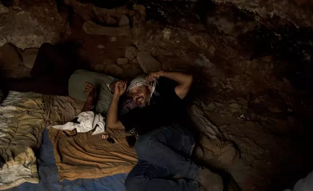 Hassan Battat takes cover from the midday heat in a cave in the West Bank village of Khirbet Zanuta, Tuesday, Aug. 27, 2024. Ten months after settlers threatened to kill them if they didn't leave their village, some Palestinian residents are finally home, under a rare court order. (AP Photo/Maya Alleruzzo)