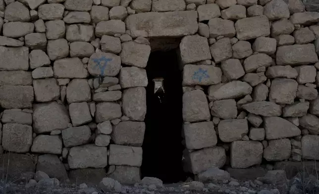 A stone house is defaced with Israeli settlers' graffiti in the West Bank village of Khirbet Zanuta, Thursday, Aug. 29, 2024. Ten months after settlers threatened to kill them if they didn't leave their village, some Palestinian residents are finally home, under a rare court order. (AP Photo/Maya Alleruzzo)