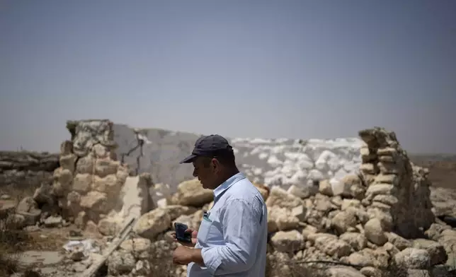 Fayez Suliman Tel, head of the village council for Khirbet Zanuta, stands next to a home that was destroyed when his community was driven out by Israeli settlers, Tuesday, Aug. 27, 2024. Ten months after settlers threatened to kill them if they didn't leave their West Bank village, some Palestinian residents are finally home, under a rare court order. (AP Photo/Maya Alleruzzo)