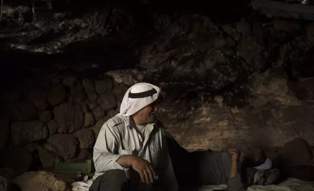 Palestinians Ribhi Ahmad Battat, left, and Issa Ahmad Battat, residents of the West Bank village of Khirbet Zanuta, take shelter from the midday sun in a cave Tuesday, Aug. 27, 2024. Ten months after settlers threatened to kill them if they didn't leave their village, some Palestinian residents are finally home, under a rare court order. (AP Photo/Maya Alleruzzo)