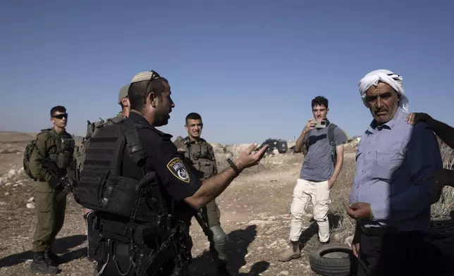 Israeli Police speak to residents of the West Bank village of Khirbet Zanuta, after activists called to report Israeli setters in the village,Thursday, Aug. 29, 2024. Ten months after settlers threatened to kill them if they didn't leave their village, some Palestinian residents are finally home, under a rare court order. (AP Photo/Maya Alleruzzo)