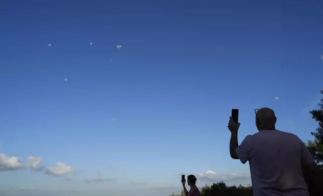 People take photos of the Israeli Iron Dome air defense system as it fires to intercept rockets that were launched from Lebanon, in Haifa, Israel, Monday, Sept. 23, 2024. (AP Photo/Baz Ratner)