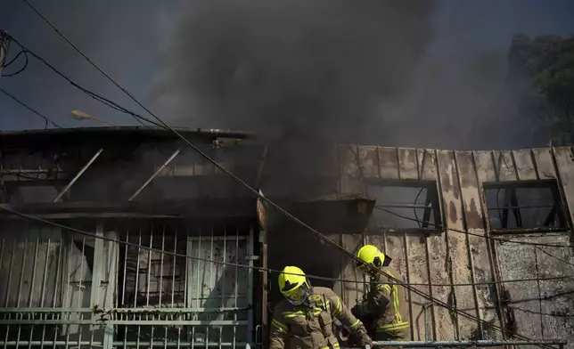 Firefighters work to extinguish a fire after a rocket, fired from Lebanon, hit a local municipality storage in Kiryat Shmona, northern Israel, Tuesday, Sept. 24, 2024. (AP Photo/Leo Correa)