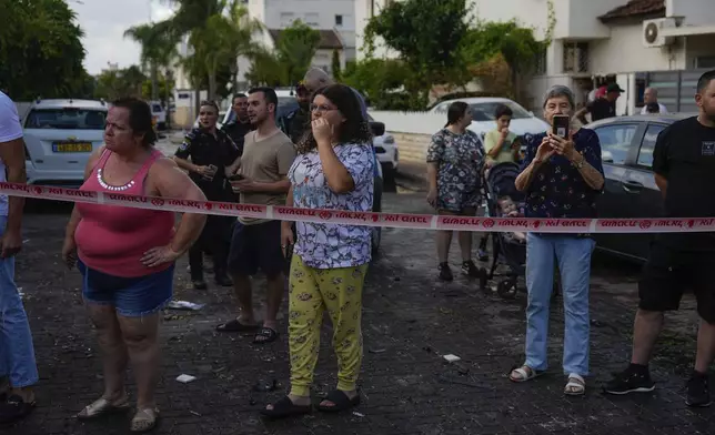 People look at the site hit by a rocket fired from Lebanon, in Kiryat Bialik, northern Israel, on Sunday, Sept. 22, 2024. (AP Photo//Ariel Schalit)