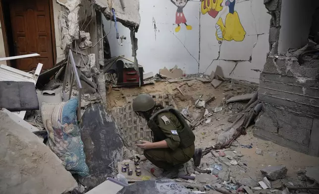 An Israeli soldier lights candles at the entrance of a tunnel where the military says six Israeli hostages were recently killed by Hamas militants in the southern Gaza Strip on Friday, Sept. 13, 2024. (AP Photo/Leo Correa)