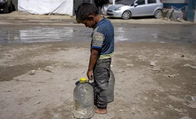 A displaced child carries filled water bottles at a makeshift tent camp in Deir al-Balah, central Gaza Strip, Thursday, Aug. 29, 2024. (AP Photo/Abdel Kareem Hana)