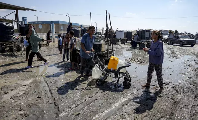 Palestinians gather to fill water jugs at a makeshift tent camp in Deir al-Balah, central Gaza Strip, Thursday, Aug. 29, 2024. (AP Photo/Abdel Kareem Hana)