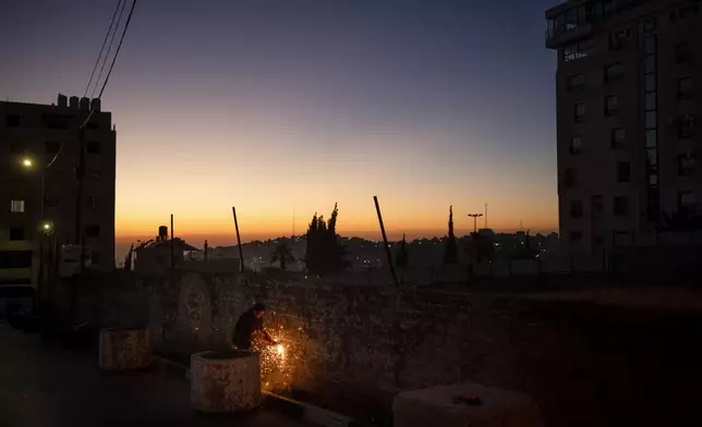 A man works on a fence at night in Hebron, West Bank, Tuesday, June 11, 2024. (AP Photo/Bram Janssen)