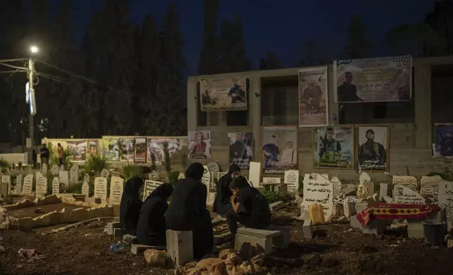 Family members sit next to the grave of Odei, 22, in Jenin, West Bank, Saturday, June 8, 2024. Odei was killed by Israeli forces during a raid inside the Jenin refugee camp. (AP Photo/Bram Janssen)