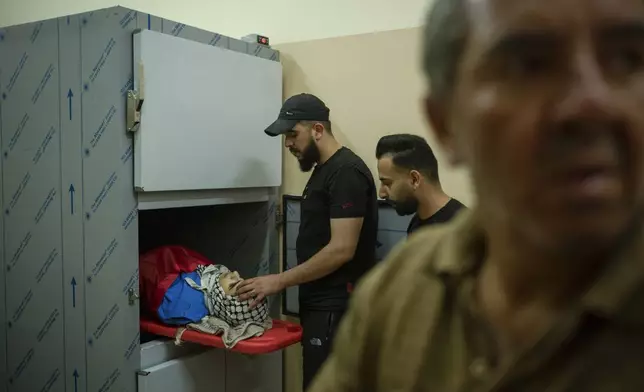 Ahmad Ibraheem Nabrisi touches the forehead of his brother, Mahmoud, 15, who was killed during a raid, inside a morgue in Tubas, West Bank, Monday, June 10, 2024. (AP Photo/Bram Janssen)