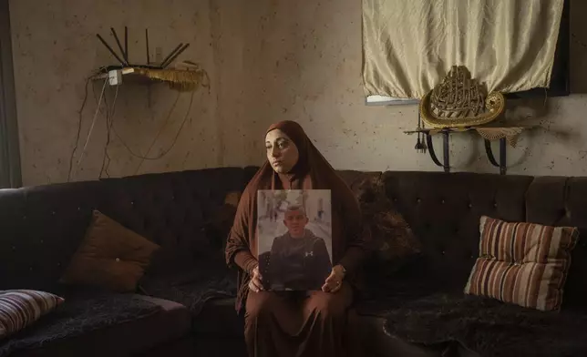 Mawaheb Morei sits for a portrait in Jenin, West Bank, Wednesday, June 5, 2024, holding a photograph of her 15-year-old son who was killed in an October 2023 drone attack. (AP Photo/Bram Janssen)