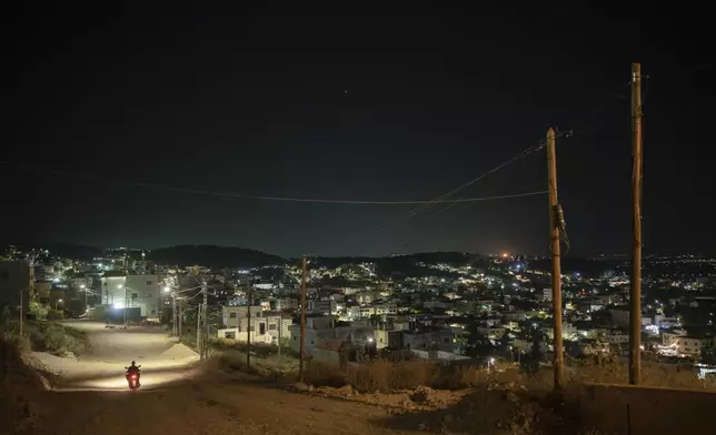 A motorcyclist drives through the hills at the Jenin refugee camp in the West Bank, Friday, June 7, 2024. (AP Photo/Bram Janssen)