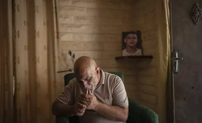 Muhamed Hajir lights a cigarette in Jenin, West Bank, Thursday, June 6, 2024, as he talks about his 15-year-old son, Osama, who was killed by Israeli forces. (AP Photo/Bram Janssen)