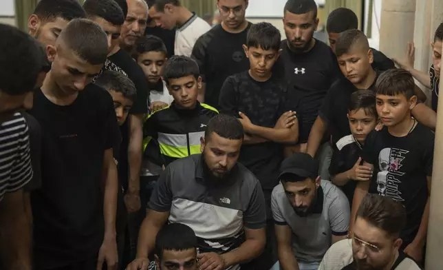 Young men and children look at the body of Palestinian militant Odei, 22, inside a mosque in Jenin, West Bank, Thursday, June 6, 2024. Odei was killed by Israeli forces during a raid inside the Jenin refugee camp. (AP Photo/Bram Janssen)