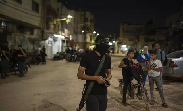 A Palestinian militant stands outside a mosque in Jenin, West Bank, Thursday, June 6, 2024. (AP Photo/Bram Janssen)