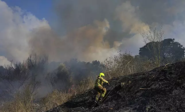 A firefighter works in the area around a fire after the military said it fired interceptors at a missile launched from Yemen that landed in central Israel on Sunday, Sept. 15, 2024. (AP Photo/Ohad Zwigenberg)