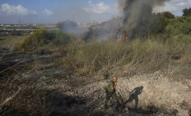 A police officer inspects the area around a fire after the military said it fired interceptors at a missile launched from Yemen that landed in central Israel on Sunday, Sept. 15, 2024. (AP Photo/Ohad Zwigenberg)