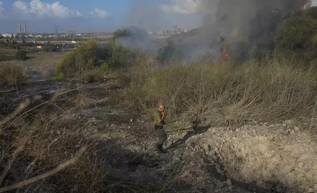 A police officer inspects the area around a fire after the military said it fired interceptors at a missile launched from Yemen that landed in central Israel on Sunday, Sept. 15, 2024. (AP Photo/Ohad Zwigenberg)