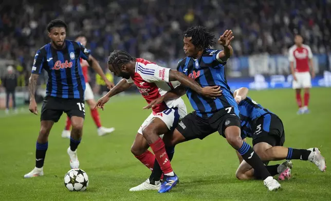 Arsenal's Raheem Sterling, centre left, and Atalanta's Juan Cuadrado challenge for the ball during the Champions League opening phase soccer match between Atalanta and Arsenal at the Bergamo's stadium in Bergamo, Italy, Thursday, Sept. 19, 2024. (AP Photo/Antonio Calanni)