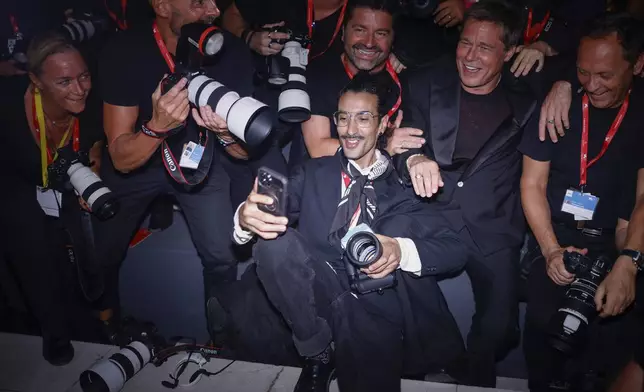 Brad Pitt, second form right, poses for a selfie with the photographers upon arrival for the premiere of the film 'Wolfs' during the 81st edition of the Venice Film Festival in Venice, Italy, on Sunday, Sept. 1, 2024. (Photo by Vianney Le Caer/Invision/AP)