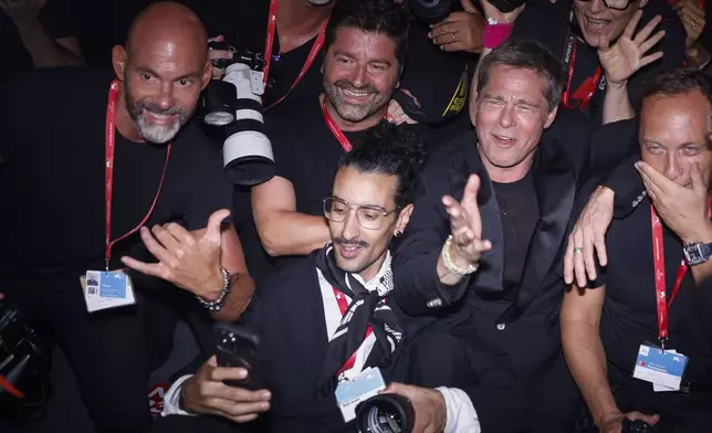 Brad Pitt, second form right, poses for a selfie with the photographers upon arrival for the premiere of the film 'Wolfs' during the 81st edition of the Venice Film Festival in Venice, Italy, on Sunday, Sept. 1, 2024. (Photo by Vianney Le Caer/Invision/AP)