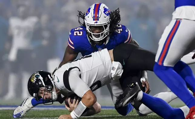 Jacksonville Jaguars quarterback Trevor Lawrence (16) lunges for yardage under Buffalo Bills linebacker Dorian Williams (42) during the first half of an NFL football game against the Buffalo Bills, Monday, Sept. 23, 2024, in Orchard Park, NY. (AP Photo/Adrian Kraus)