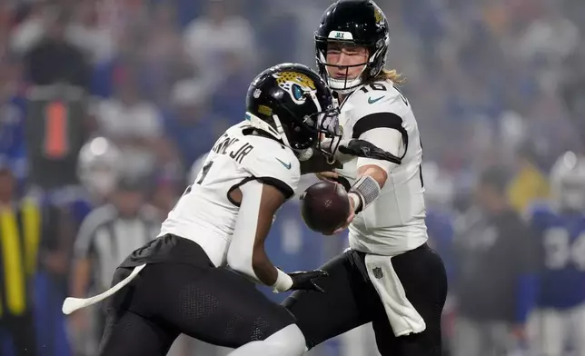 Jacksonville Jaguars quarterback Trevor Lawrence (16) hand off to running back Travis Etienne Jr. (1) during the first half of an NFL football game against the Buffalo Bills, Monday, Sept. 23, 2024, in Orchard Park, NY. (AP Photo/Steven Senne)