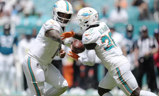 Miami Dolphins quarterback Tua Tagovailoa (1) hands the ball to running back De'Von Achane (28) during the first half of an NFL football game against the Jacksonville Jaguars, Sunday, Sept. 8, 2024, in Miami Gardens, Fla. (AP Photo/Rebecca Blackwell)