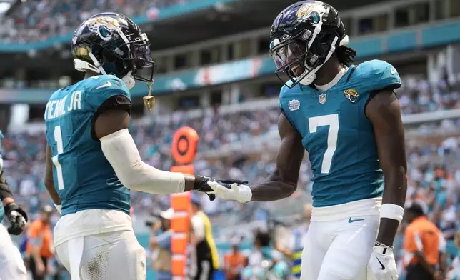 Jacksonville Jaguars wide receiver Brian Thomas Jr. (7) celebrates after scoring a touchdown with running back Travis Etienne Jr. (1) during the first half of an NFL football game against the Miami Dolphins, Sunday, Sept. 8, 2024, in Miami Gardens, Fla. Etienne Jr. scored a touchdown earlier in the game. (AP Photo/Rebecca Blackwell)