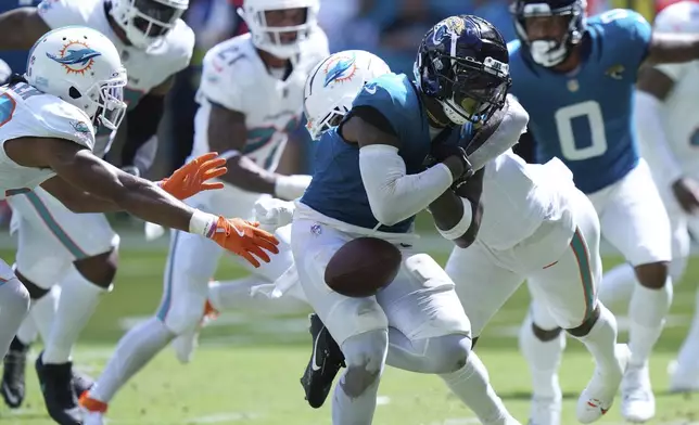 Jacksonville Jaguars running back Travis Etienne Jr. (1) fumbles the ball during the second half of an NFL football game against the Miami Dolphins, Sunday, Sept. 8, 2024, in Miami Gardens, Fla. (AP Photo/Wilfredo Lee)