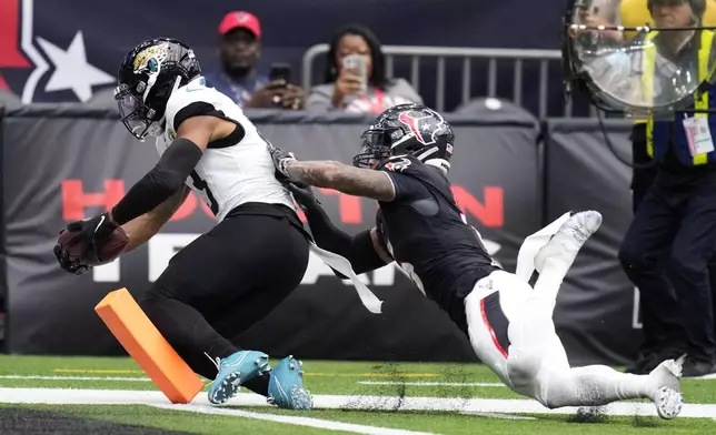 Jacksonville Jaguars wide receiver Christian Kirk catches an 8-yard touchdown pass in front of Houston Texans safety Jalen Pitre, right, during the second half of an NFL football game, Sunday, Sept. 29, 2024, in Houston. (AP Photo/Eric Christian Smith)