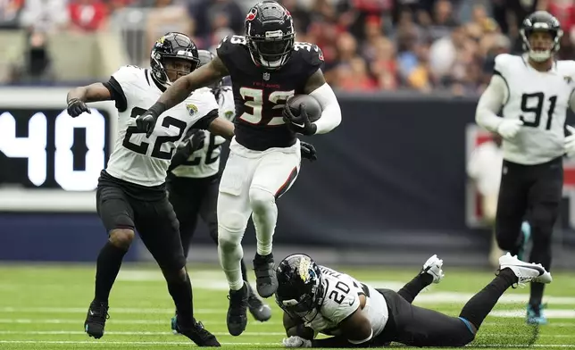 Houston Texans running back Dare Ogunbowale (33) runs from Jacksonville Jaguars safety Daniel Thomas (20) and cornerback Jarrian Jones (22) during the second half of an NFL football game, Sunday, Sept. 29, 2024, in Houston. (AP Photo/Eric Gay)