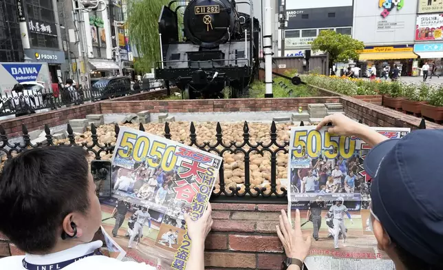 Pedestrians read an extra edition of the Sports Nippon newspaper reporting on the Los Angeles Dodgers' Shohei Ohtani becoming the first player in major league history with 50 home runs and 50 stolen bases in a season, Friday, Sept. 20, 2024, in Tokyo. (AP Photo/Eugene Hoshiko)