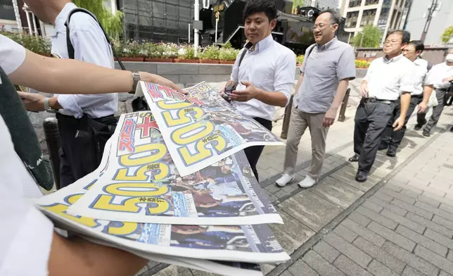 Pedestrians line up to obtain an extra edition of the Sports Nippon newspaper reporting on the Los Angeles Dodgers' Shohei Ohtani becoming the first player in major league history with 50 home runs and 50 stolen bases in a season, Friday, Sept. 20, 2024, in Tokyo. (AP Photo/Eugene Hoshiko)