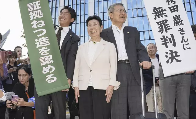 Hideko Hakamada, center, sister of 88-year-old former boxer Iwao Hakamada who has been on death row for nearly six decades after his murder conviction that his lawyers said was based on forced confession and fabricated evidence, reacts after a court ruled that her brother was not guilty in a retrial for a 1966 quadruple murder, in front of the court in Hamamatsu, Shizuoka prefecture, Thursday, Sept. 26, 2024. The signs read "Acquittal to Mr. Iwao Hakamada, " right, and "Acknowledged fabrications of evidence." (Kyodo News via AP)