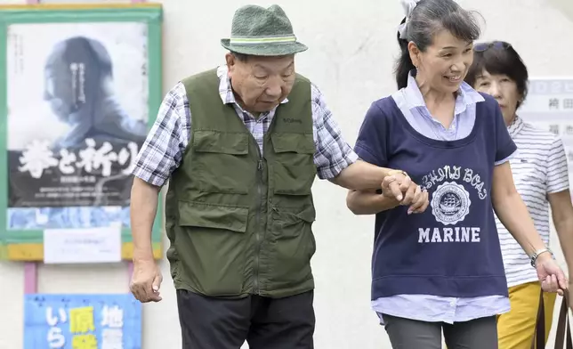 Iwao Hakamada, left, 88-year-old former boxer who has been on death row for nearly six decades after his murder conviction that his lawyers said was based on forced confession and fabricated evidence, is helped by a supporter as he goes for a walk in Hamamatsu, Shizuoka prefecture, central Japan Wednesday, Sept. 25, 2024. (Kyodo News via AP)