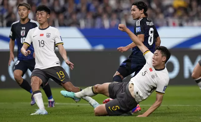 Japan's Takumi Minamino, center , scores a goal past China's Zhu Chenjie, bottom during a World Cup and AFC Asian Qualifier at Saitama Stadium 2002 in Saitama, north of Tokyo, Thursday, Sept. 5, 2024.(AP Photo/Shuji Kajiyama)