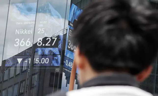 A person walks in front of an electronic stock board showing Japan's Nikkei index at a securities firm Friday, Sept. 13, 2024, in Tokyo. (AP Photo/Eugene Hoshiko)