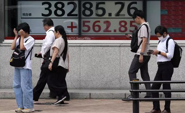 People walk in front of an electronic stock board showing Japan's Nikkei index at a securities firm Tuesday, Sept. 24, 2024, in Tokyo. (AP Photo/Eugene Hoshiko)