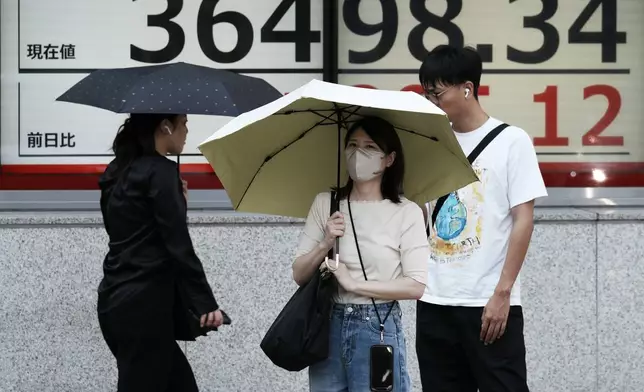 People stand in front of an electronic stock board showing Japan's Nikkei index at a securities firm Wednesday, Sept. 18, 2024, in Tokyo. (AP Photo/Eugene Hoshiko)