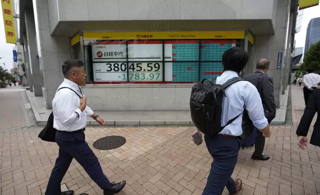 People walk by monitors showing Japan's Nikkei 225 index at a securities firm in Tokyo, Monday, Sept. 30, 2024. (AP Photo/Hiro Komae)