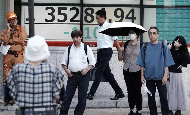 People stand near an electronic stock board showing Japan's Nikkei index at a securities firm Monday, Sept. 9, 2024, in Tokyo. (AP Photo/Eugene Hoshiko)