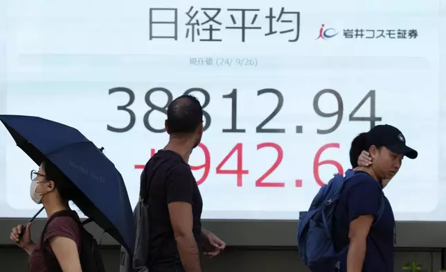 People walk in front of an electronic stock board showing Japan's Nikkei index at a securities firm Thursday, Sept. 26, 2024, in Tokyo. (AP Photo/Eugene Hoshiko)