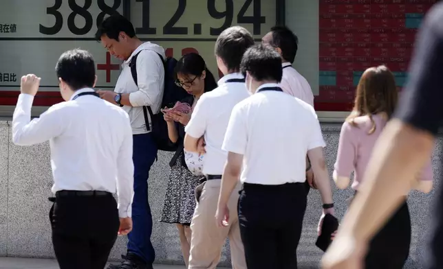 People walk in front of an electronic stock board showing Japan's Nikkei index at a securities firm Thursday, Sept. 26, 2024, in Tokyo. (AP Photo/Eugene Hoshiko)