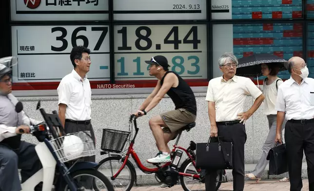 People stand in front of an electronic stock board showing Japan's Nikkei index at a securities firm Friday, Sept. 13, 2024, in Tokyo. (AP Photo/Eugene Hoshiko)